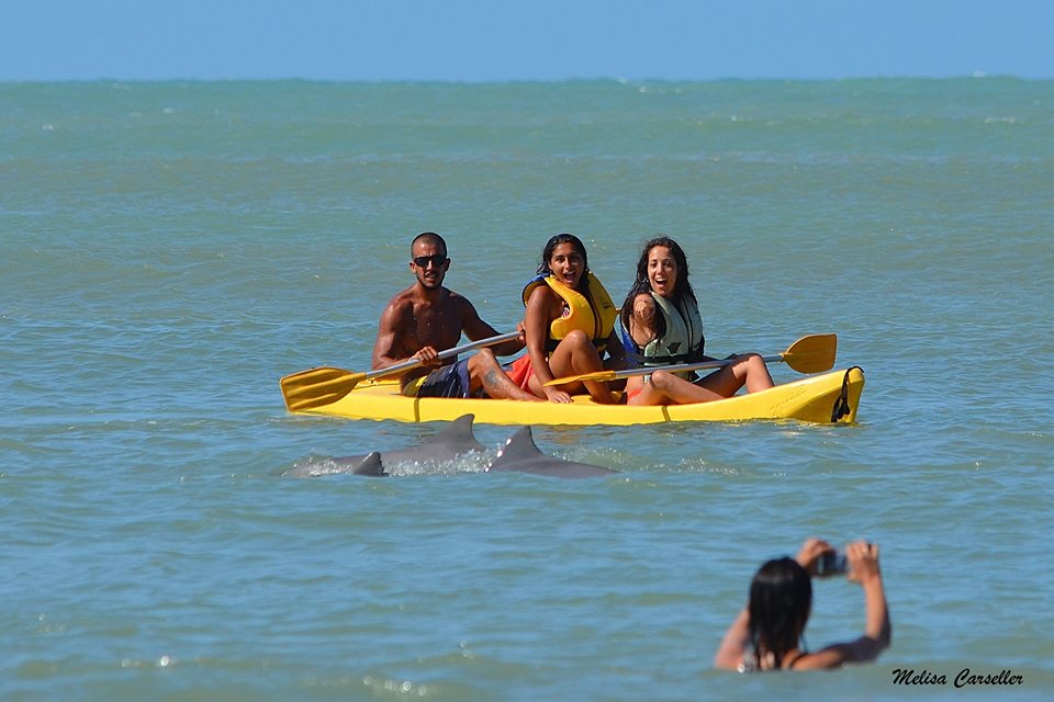 Três pessoas sorrindo em um caiaque amarelo