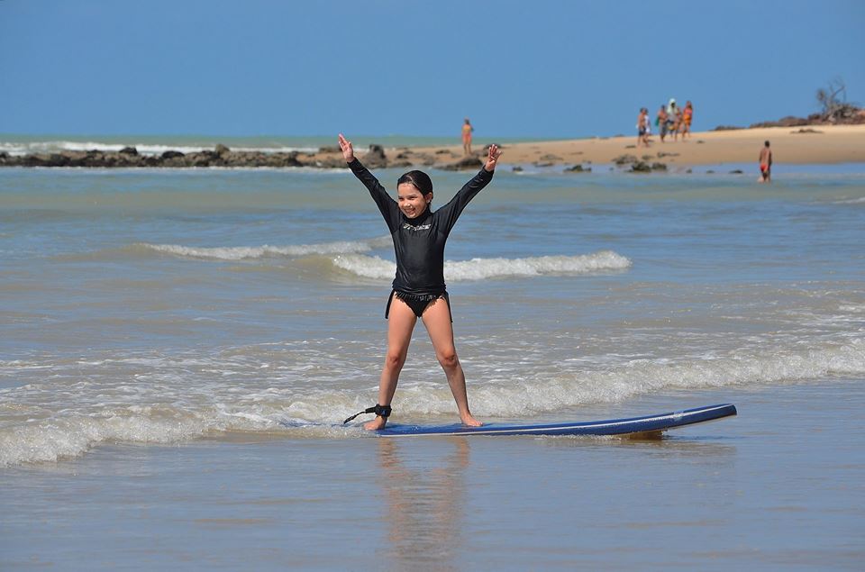 Aluna da Pipa Surf School comemorando em pé na prancha